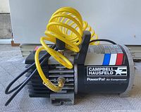 Portable Campbell Hausfeld PowerPal air compressor with attached coiled yellow air hose.