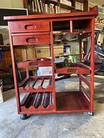 Front view of wooden wine rack trolley with drawers, wine bottle racks, removable trays, stone top, and caster wheels.