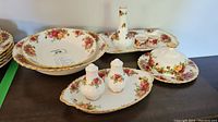 Photo showing round serving bowl, tray with condiment bottle, and pair of salt and pepper shakers with tray, plus plate with dome in Royal Albert Old Country Roses pattern.