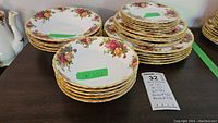 Five stacked 10 inch dinner plates, five 8 inch plates, six 6.5 inch plates, and two stacks of five bowls each on a dark surface showing floral pattern and gold trim.
