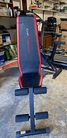 Full view of Capstrength adjustable utility weight bench showing padded black and red backrest, steel frame, and foam leg holders.