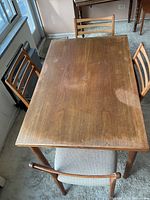 Overhead view of dining table with four chairs around showing overall condition of table top and seating arrangement