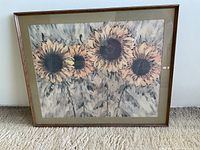 Full front view of framed sunflower art print featuring muted pastel colors and five large sunflowers. Frame is wood with glass panel.