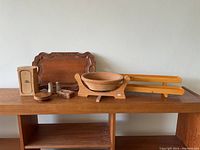 View of all wooden items on a wooden shelf showing tray, bowl, stand, salt and pepper shakers, and other small wooden pieces.