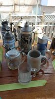 Overview of collection showing various beer steins, mugs including ceramic, glass and one dog-shaped ceramic pitcher