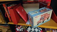 Shelf of Coca-Cola books, binders, and the boxed remote control truck