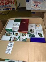 Open cardboard box showing assorted Department 56 boxed figurines