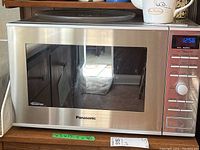 Front view of the Panasonic Inverter microwave showing stainless steel finish and glass door.