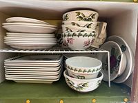 Full view of shelf showing stacks of plates, bowls and serving pieces with botanical patterns