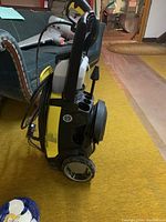Side view of the Karcher K5-65 power washer showing the body, wheels, handle and coiled hose.