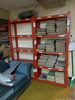 Front view of two orange plastic shelving units loaded with stacked papers and cardboard