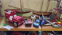 Photo of toy collection showing Tonka Jeep, model boats, various toys, candy dispenser