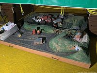 Full shot of the train layout showing track, buildings, hills, and tunnels on a large rectangular base with handles.