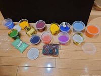 Photo of multiple plastic containers filled with small colored beads in a variety of colors including green, yellow, purple, blue, orange, red, and white.