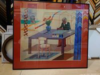 Framed offset lithograph showing a self-portrait of David Hockney sitting at a table with paint pots, colorful interior.