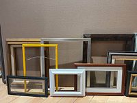 Full view of the lot showing various picture frames of different colors and sizes arranged upright against a wall.