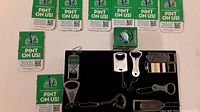 Photo showing eight green and white Steam Whistle branded vouchers for a free pint and various metal bottle openers and bike bell presented on a flat surface.