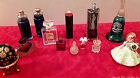 Front side view of vintage perfume bottles and Josef Originals figurine arranged on red surface.