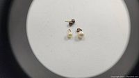 Image showing small black button pearl stud earrings and two white pearl pendants with gold loops.