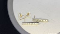 Two pairs of 14k gold stud earrings: one open-heart pair and one bar pair with embedded Swarovski stones.