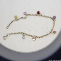 Close-up view of silver bracelet with small square-cut multi-colored tourmaline stones spaced along the chain.
