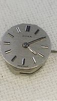 Front view of Doxa watch movement showing silver dial with hour markers and hands.