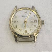 Front view of Dynasty watch showing white dial with gold-tone numbers, date window, and luminous hands