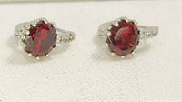 Front view of the sterling silver garnet earrings on a white background showing the deep red garnet stones in prong settings with hoop design