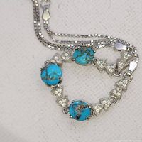 Close-up photo of the bracelet showing three round turquoise stones set among triangular diamond-studded accents on a box chain.