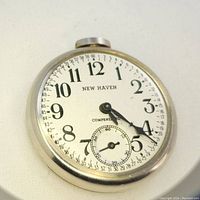 Close-up of New Haven pocket watch face displaying white dial, black Arabic numerals, subsidiary seconds dial, and text 'NEW HAVEN' and 'COMPENSATED'.