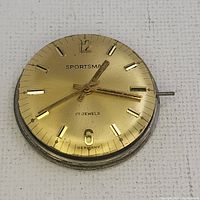 Close up photo of gold tone Sportsman watch dial and hands, showing 'SPORTSMAN', '17 JEWELS', and 'GERMANY' text.