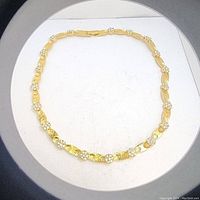 Top view of the full gold-tone statement choker necklace arranged in a circle on white background.