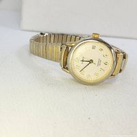 Front view of vintage Timex Indiglo quartz watch showing watch face, gold-tone case, and expandable metal band.