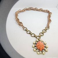 Full view of Yoska large statement necklace with two-tone chain and large floral coral pendant.