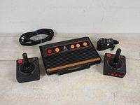 Photo showing Atari Flashback 8 Gold console with two wireless joystick controllers and power adapter, HDMI cable.
