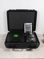 Custom black storage case open showing Original Xbox console, controller, game, and cables inside.