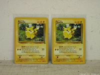 Front view of two Pikachu Pokemon cards from the base set, numbered 60/64, showing the artwork and card details.