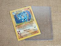 Front of Pokemon Machamp holographic card, sealed in plastic sleeve, showing the card details and 1st Edition stamp.