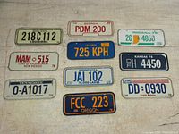 Front view of ten vintage 1978 cereal box bicycle license plates arranged in two rows on a fabric surface.