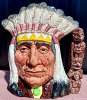 Front detailed view of Royal Doulton toby jug showing Indian chief face with feathered headdress and green medallion.