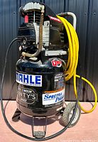 Full front view of the upright compressor showing tank, pump, handle, wheels, and attached yellow hose