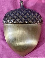 Front view of the large acorn-shaped brass door knocker showing detailed textured acorn cap and smooth lower body.