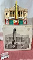 Front view of the Department 56 Paramount Theatre model on top of its original box showing front facade with marquee and ticket booth.
