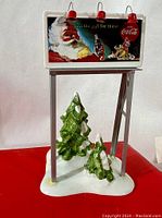 Front view of the Department 56 Coca-Cola billboard accessory displaying Santa Claus holding a Coca-Cola bottle with festive holiday imagery and text.
