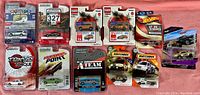 Overall lot of various diecast cars in original packaging on pink surface
