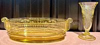Yellow Fostoria etched glass bowl with curled handles shown front and side