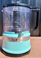 Food processor base with turquoise finish and silver KitchenAid logo on the front, showing compact design and condition.