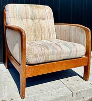Front angled view of armchair showing teak frame and upholstered cushions.