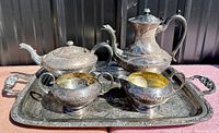 Photo of the EPNS silver plated coffee and tea set including coffee pot, tea pot, creamer, sugar bowl, all placed on the ornate tray showing detailed engravings and gold-tone interiors in some pieces.