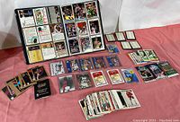 Wide shot showing multiple stacks and groups of basketball and hockey cards laid out, including cards in protective sleeves and loose cards.